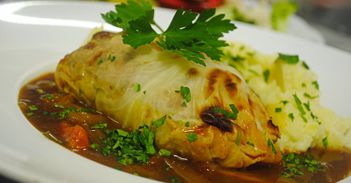 Hausgemachte Spitzkohlroulade mit Schmorfond und Meerrettichstampf auf dem Teller – Mittagstisch im Restaurant Artischocke Wilhelmshaven