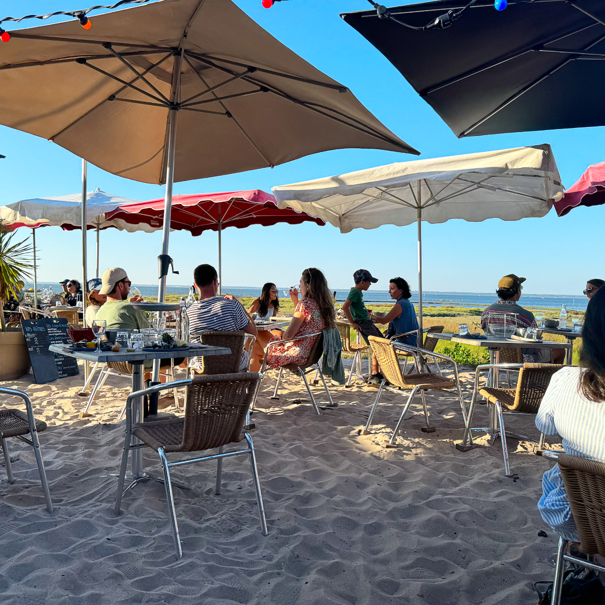 Strandrestaurant mit Sonnenschirmen und Gästen direkt am Sand im Bassin d'Arcachon, Frankreich